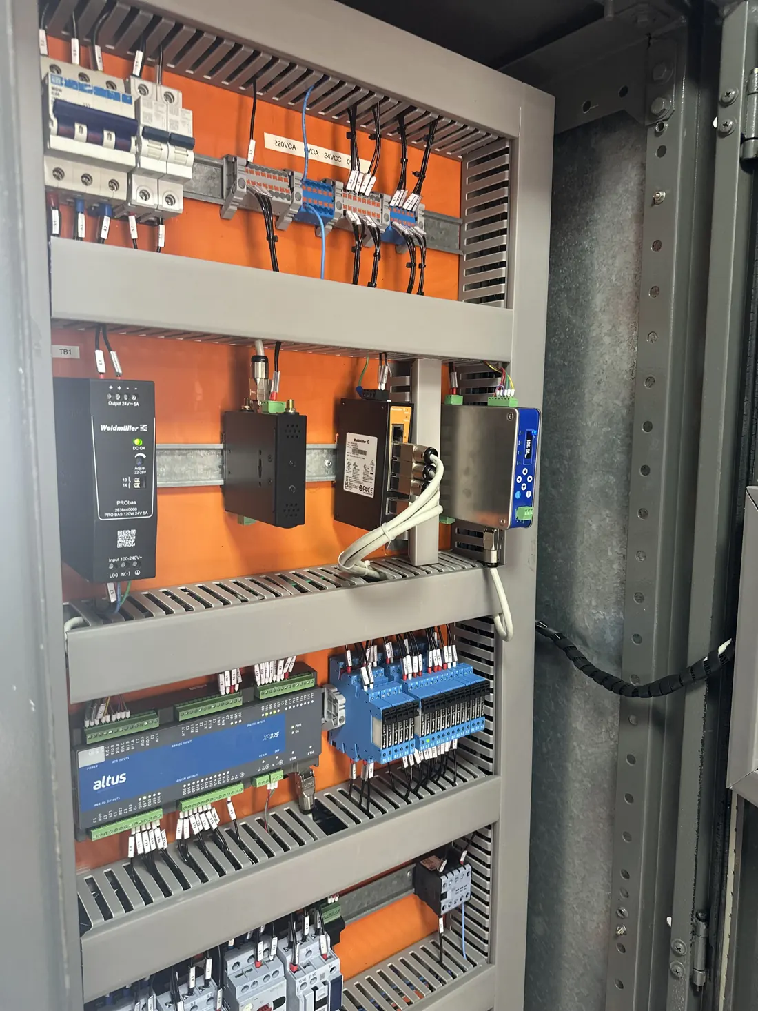 Interior de painel com CLP, fonte, switch industrial e relés de interface